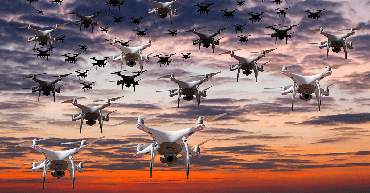 aerial-drone-swarm Multiple drones flying in formation against a dramatic sunset sky.
